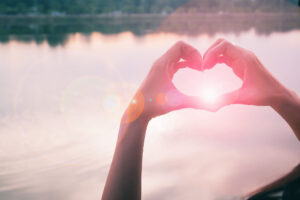 Hand geformt zum Herz mit Wasser und Sonnenstrahlen